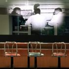 four chairs at a counter in front of a black and white photograph of the Greensboro Four