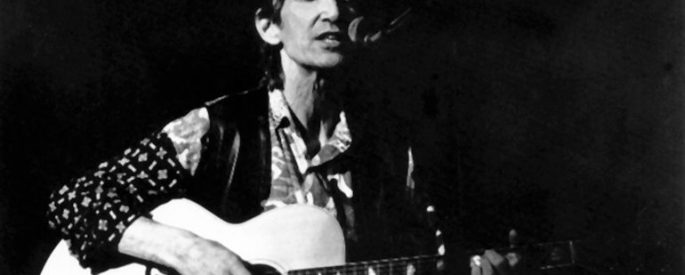 Townes Van Zandt with a guitar, singing into a microphone
