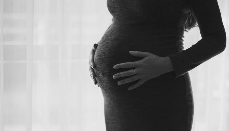 black and white image of the midriff of a pregnant woman in a dress