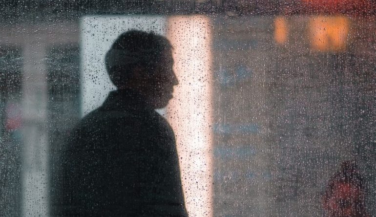 silhouette of a person through a dewy window