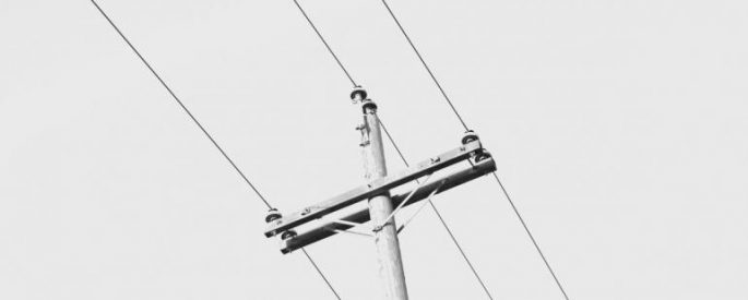 view from the ground of a telephone pole with wires