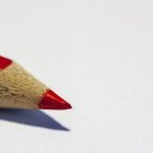 a red colored pencil against a white background