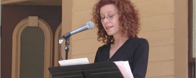 woman speaking at a stand with a microphone