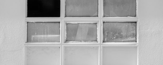 Black and white image of a window with a missing pane.