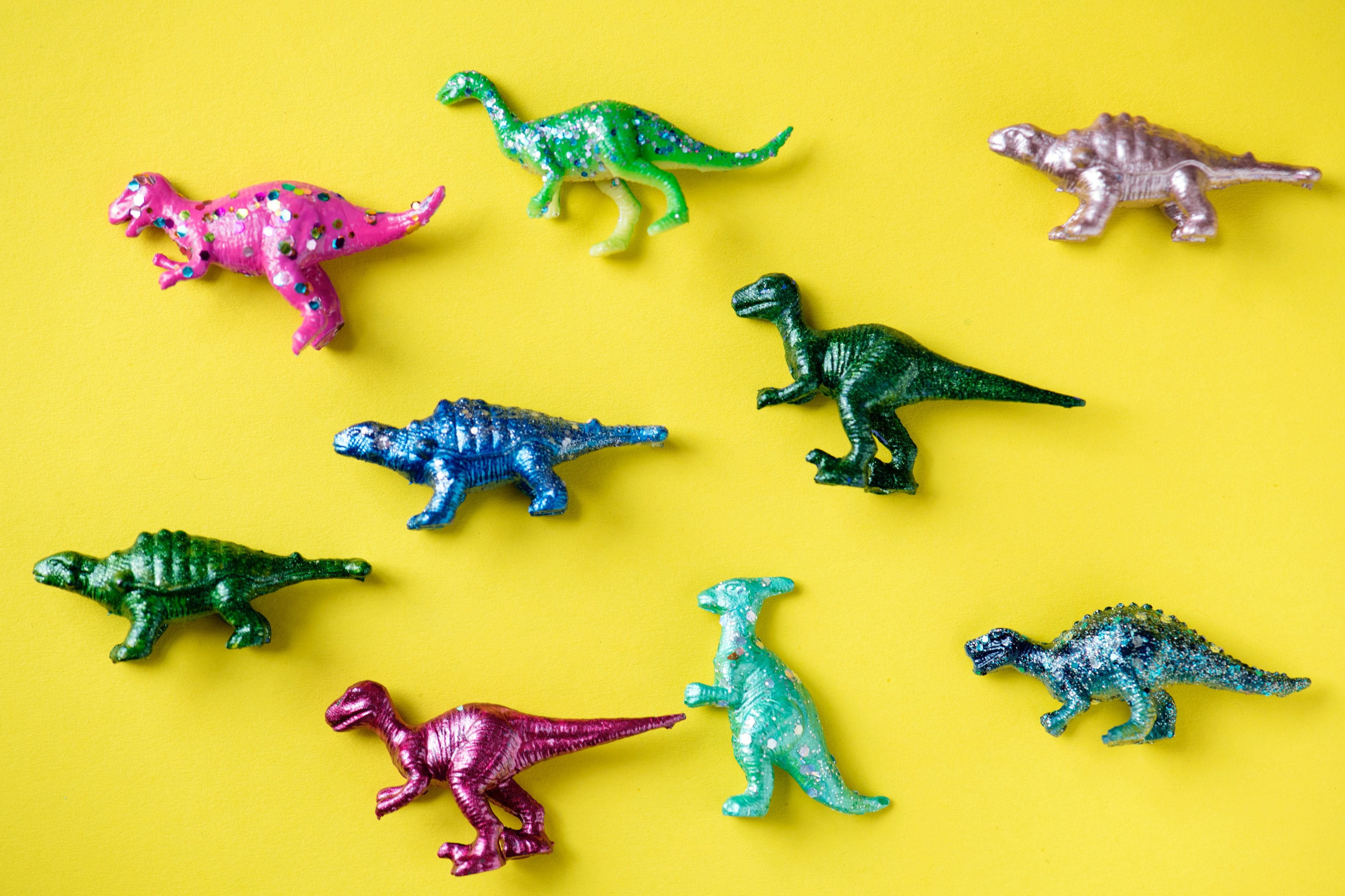 Bright colored dinosaur toys played out against a bright yellow background.