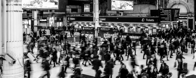 Black and white, blurred photograph of a crowd in a large train station