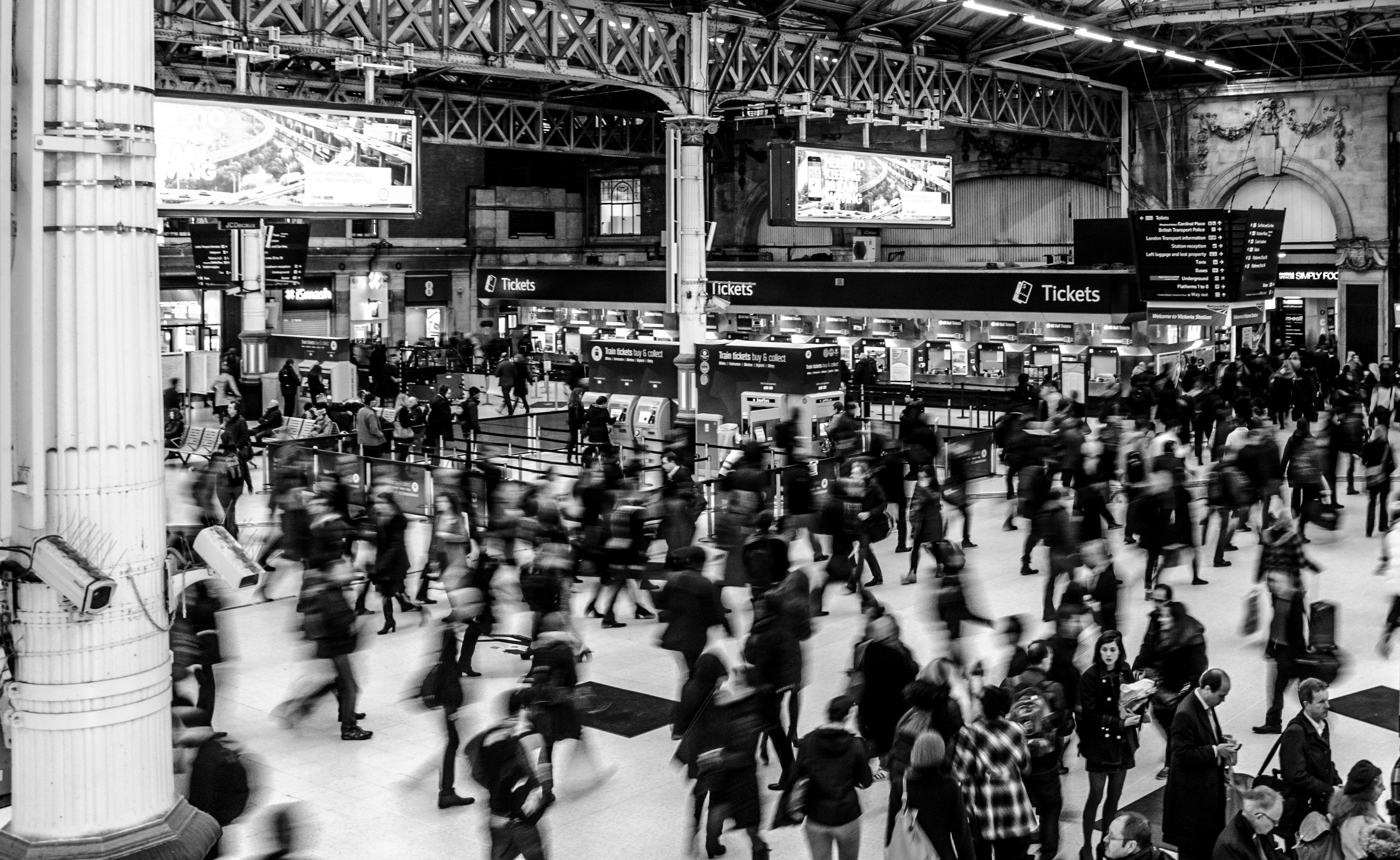 Black and white, blurred photograph of a crowd in a large train station