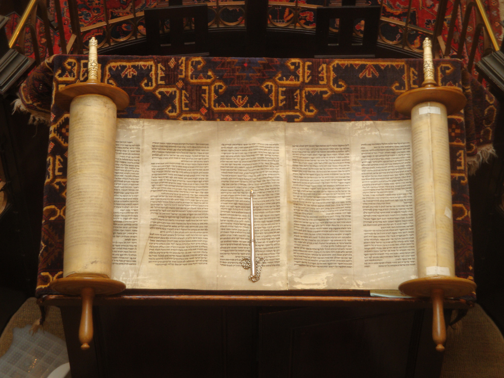 Photograph of an old Torah scroll open and resting on a wooden table