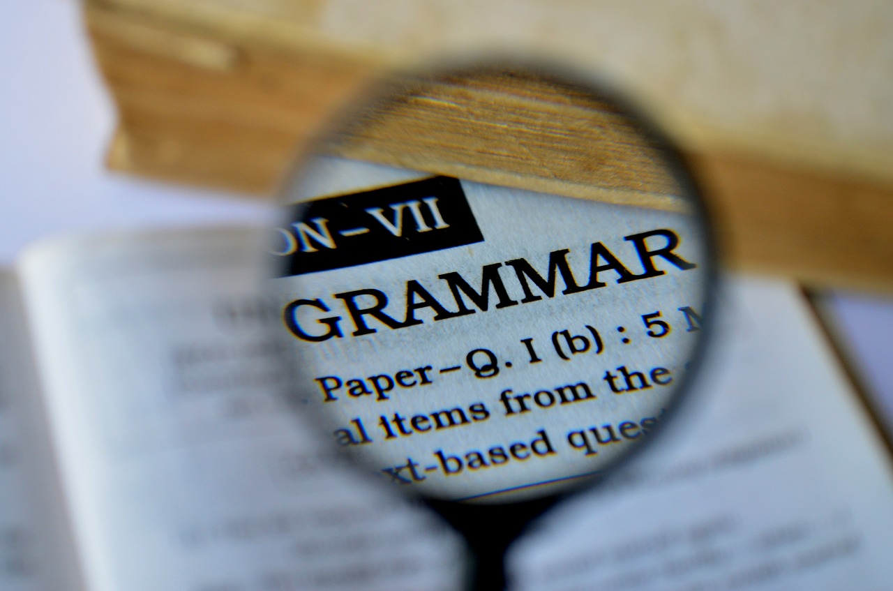 Photograph of a magnifying glass over the dictionary definition of "grammar"