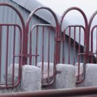 image shows a series of red, rusting gates side by side