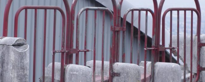image shows a series of red, rusting gates side by side