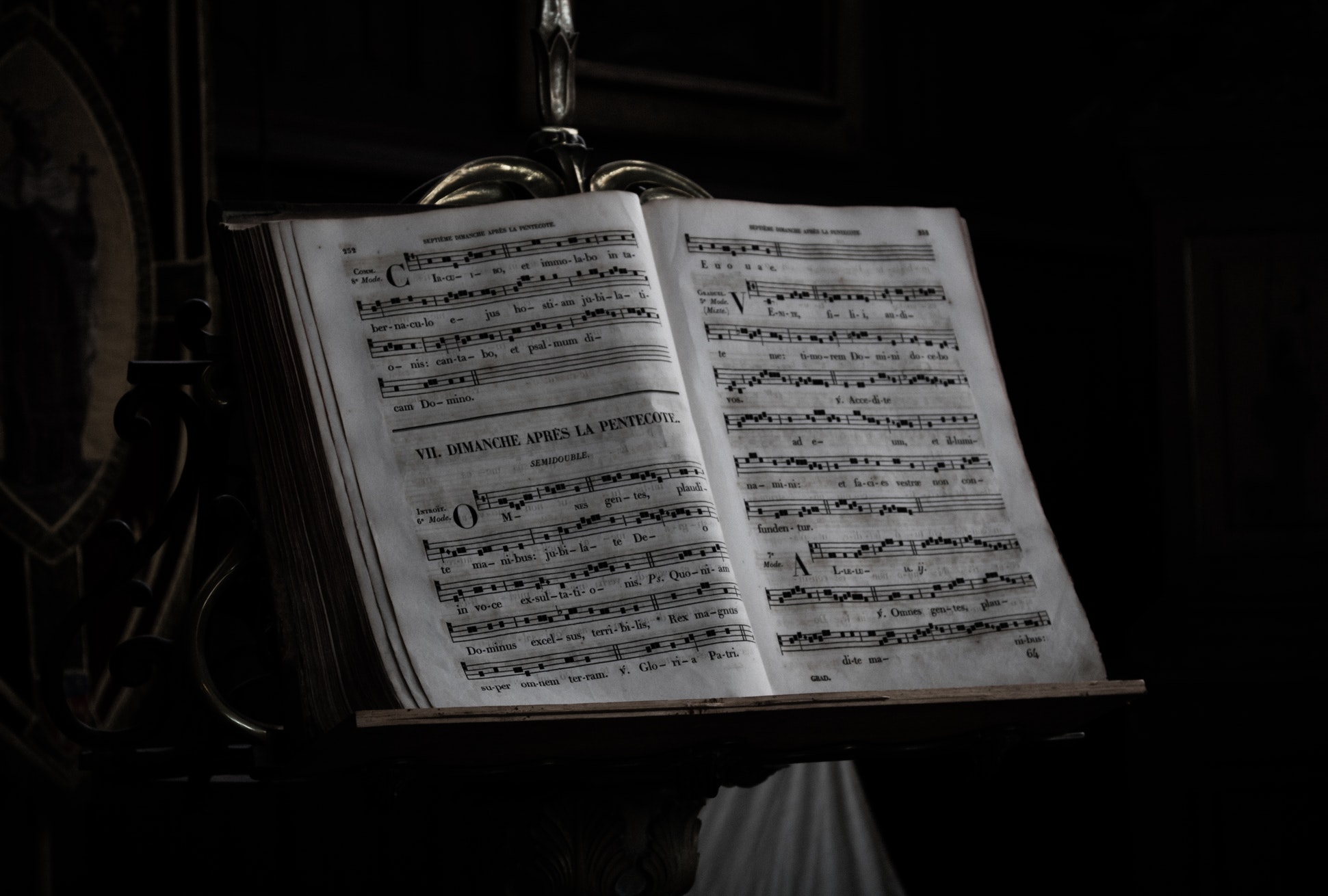 Sheet music sits atop a music stand in a dark room.