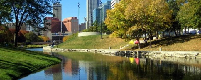 image of Downtown Omaha city skyline in a bright, sunlit park with a lake