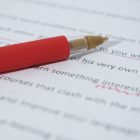 A red pen rests on top of a manuscript.