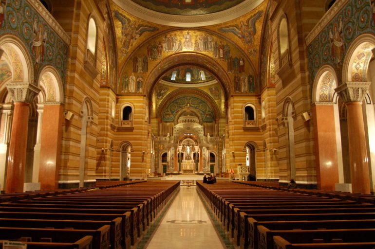 image is of the Cathedral Basilica of St. Louis featuring rows of pews and impressive architecture 