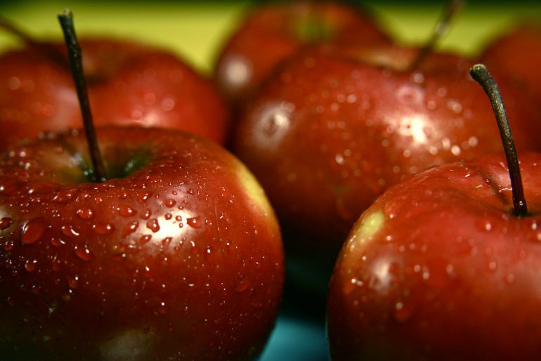 a bunch of red apples with drops of condensation on them