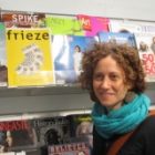 photo of a woman in a turquoise scarf in front of a newsstand of magazines