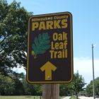 photo of a sign that points to "Oak Leaf Trail" ahead in brown and gold lettering, an oak leaf accompanies the words