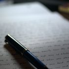 photo of a pen on a page filled the hand-written text