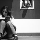 black and white photo of a woman reading against a wall