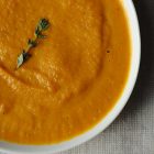an up-close photograph of a bowl of bright orange Roasted Carrot Soup