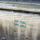 a wood plank with the words "I can feel your smile" written in sharpie