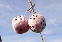 a photograph of a pair of large pink fuzzy dice suspended in the air