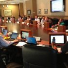 Group of people sitting around a conference table with laptops