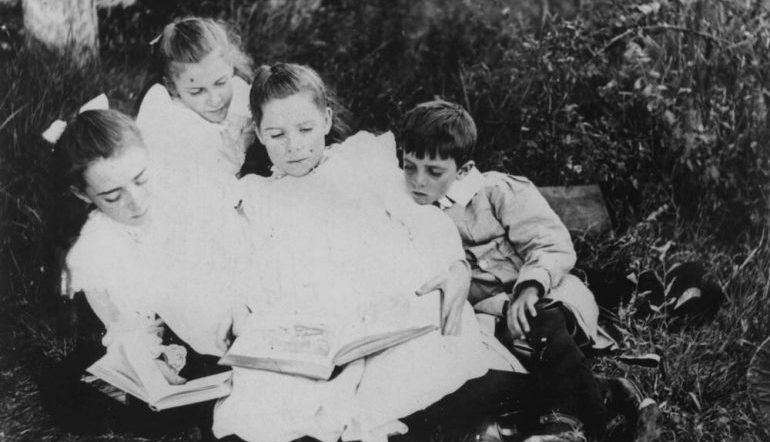 Vintage photo of children huddled around one book reading together