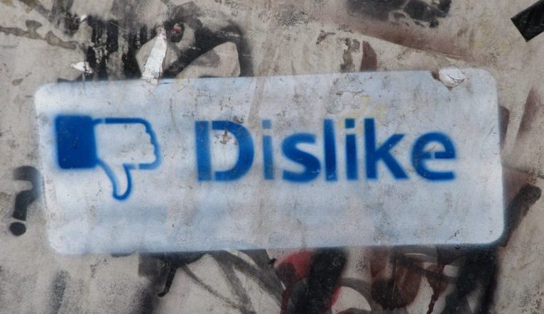 Graffit on a concrete wall with the Facebook "Dislike" thumbs down