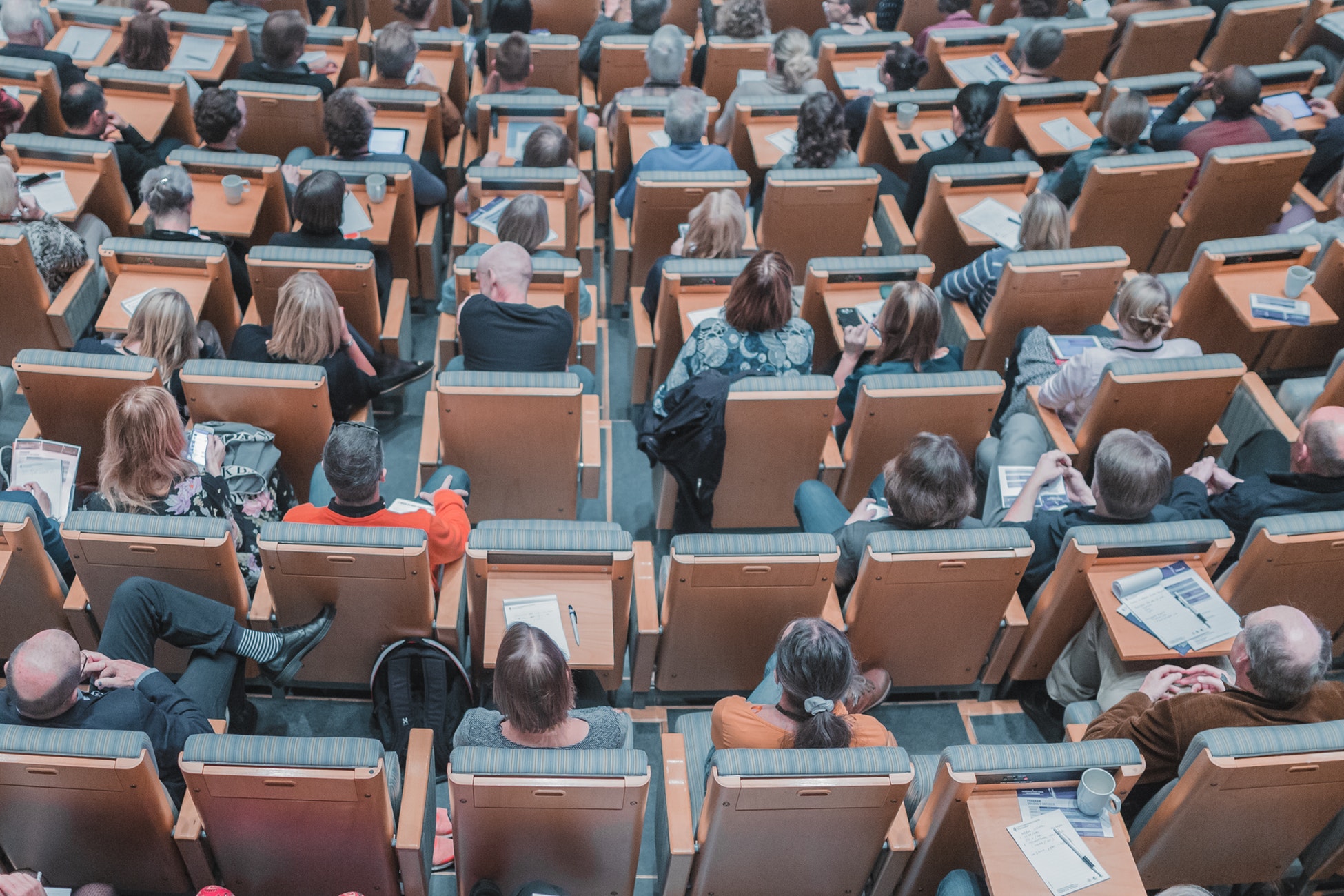 A birds eye view of a lecture hall with people sitting in the chairs.