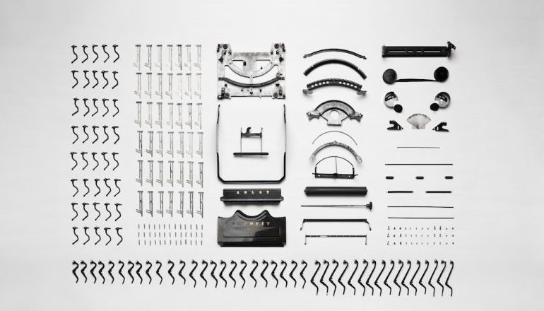 Picture of a typewriter taken apart, all of the pieces lined up side by side