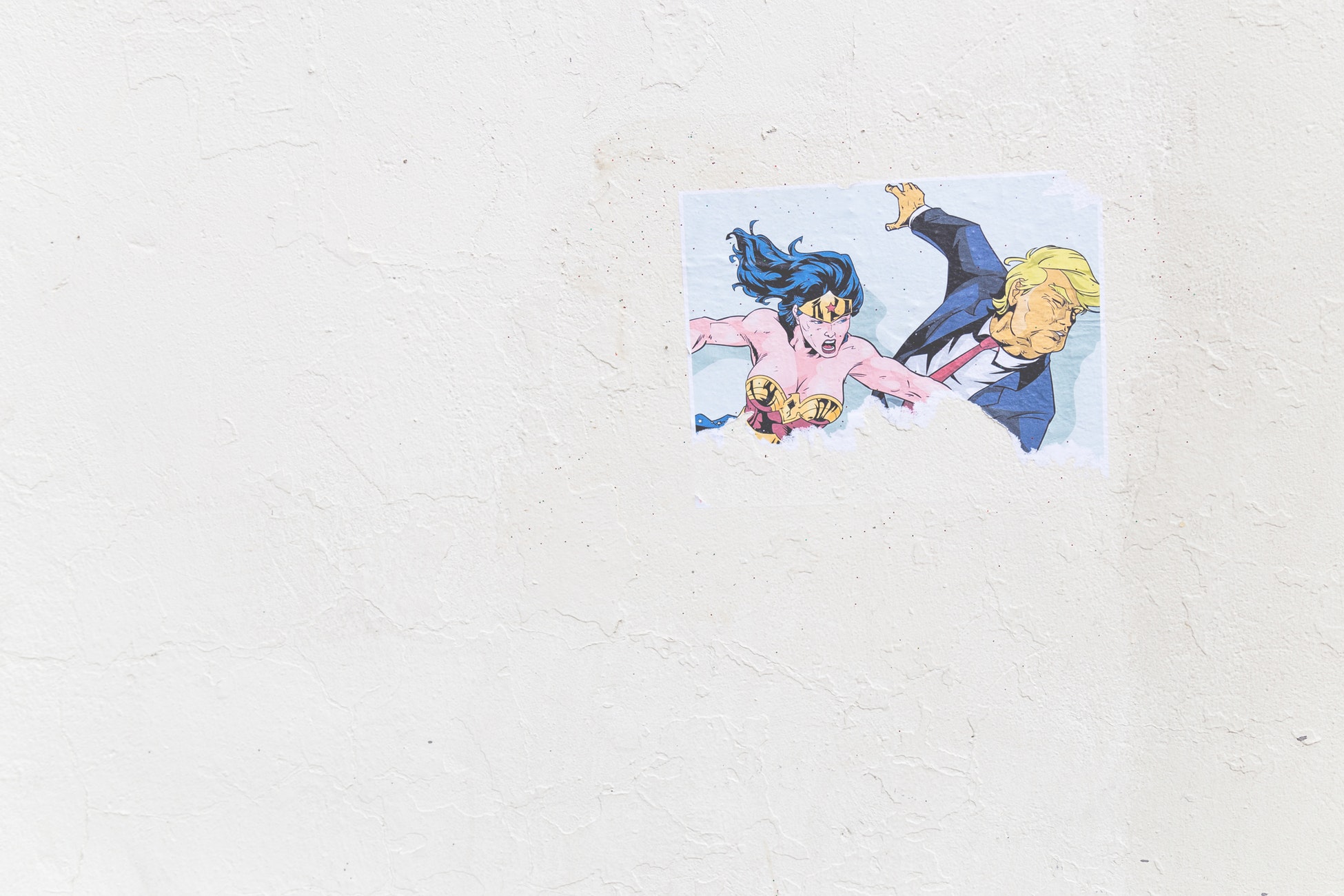 Picture of a trump and wonder woman sticker on a white wall