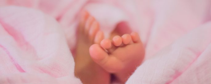 Baby feet on pink blanket.