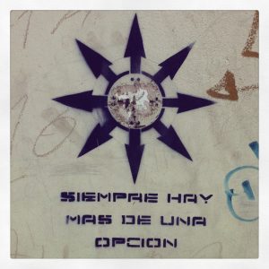 Picture of a graffitied arrows pointing on many directions on a wall with the words "Siempre hay mas de una opcion" (There's always more than one option) on the wall