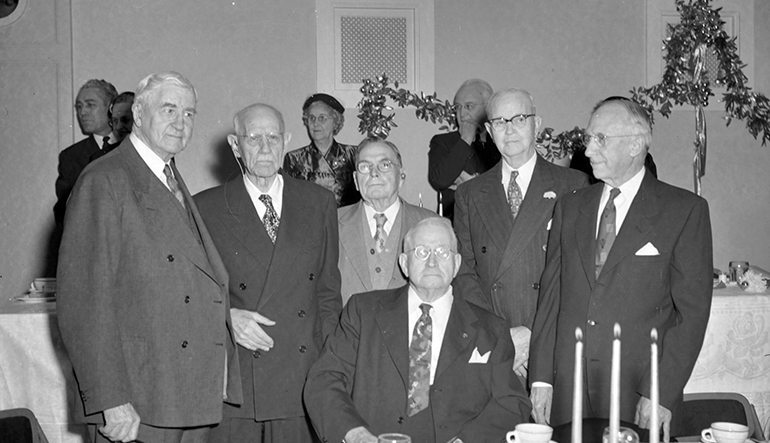 Several older men dressed in suits posing for photograph.