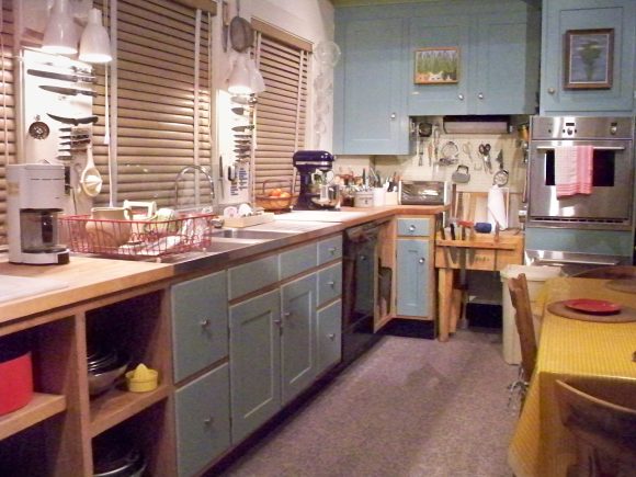 Colorful kitchen with blue cupboards and a yellow tablecloth.