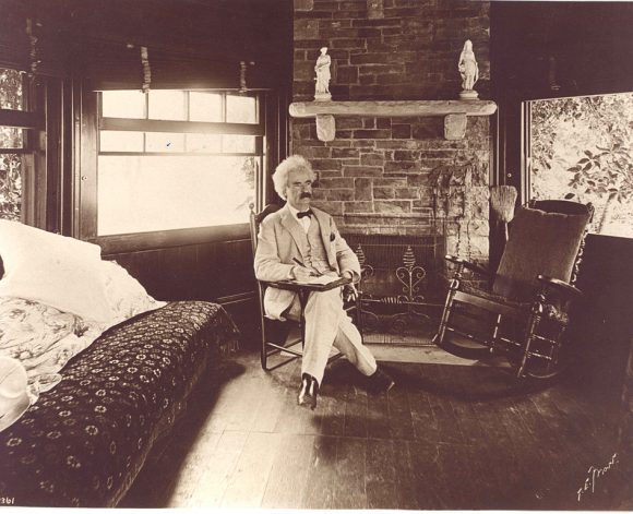 Man in a suit sitting in an old bedroom.