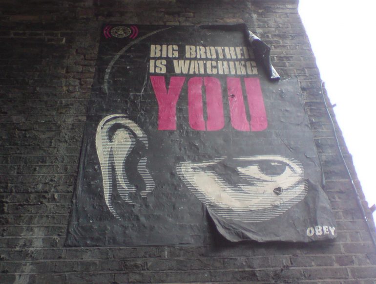 Poster on the side of a wall that reads "Big Brother is Watching YOU."