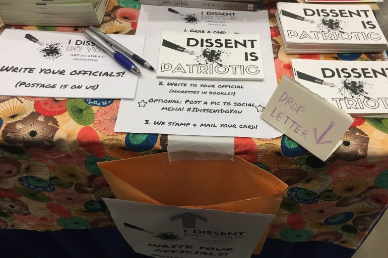 Papers reading "Dissent is Patriotic" on a table, with an open envelope on the side.