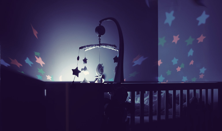 Baby mobile hanging above crib and projecting stars onto wall.