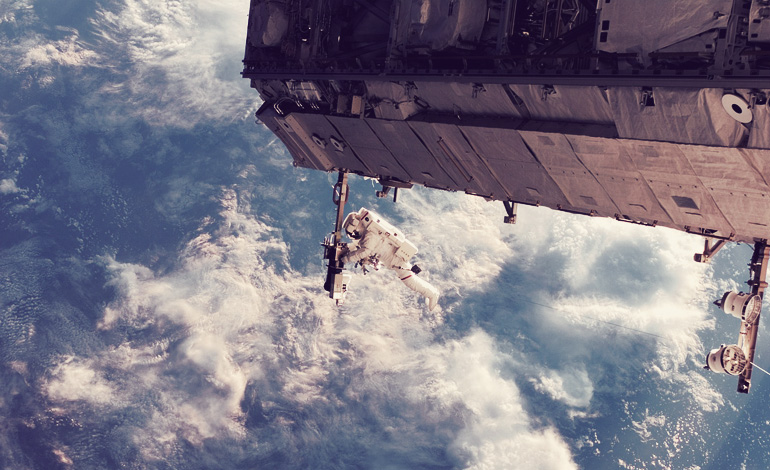 Astronaut floating out of a space ship above the Earth.