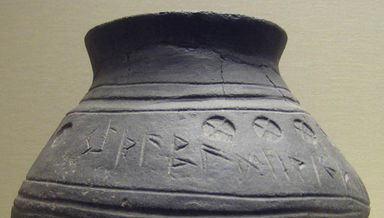 Large pot with symbols carved into it.