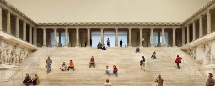 people sitting on wide steps inside a museum