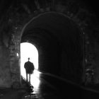 shadowing person walks under a tunnel