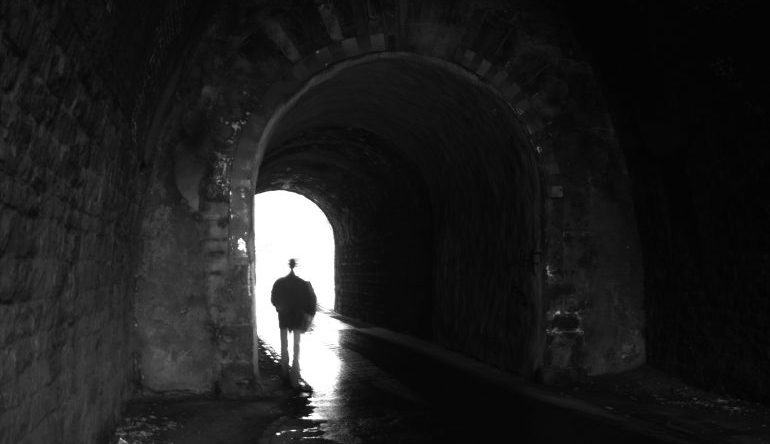 shadowy person walks under a tunnel