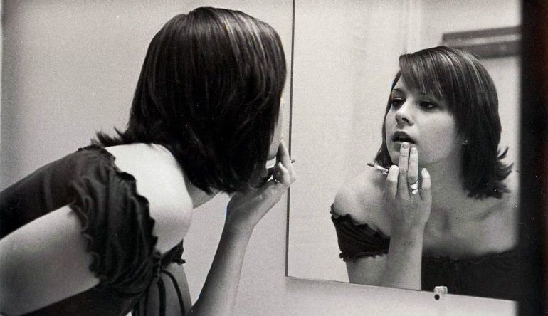 woman checking her lipstick in the mirror