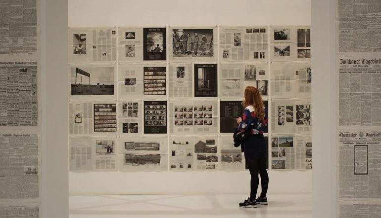 woman looking at a wall of what appear to be newspaper pages