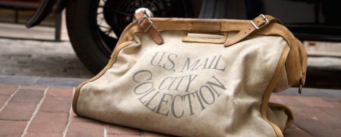 bag with lettering that reads "U.S. MAIL CITY COLLECTION" on a brick sidewalk