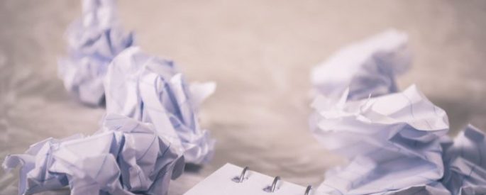 crumpled balls of paper around a corner of a notebook